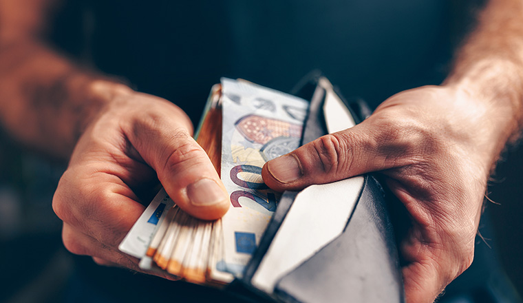 Stack of euros in a wallet - purchasing power - male hands closeup