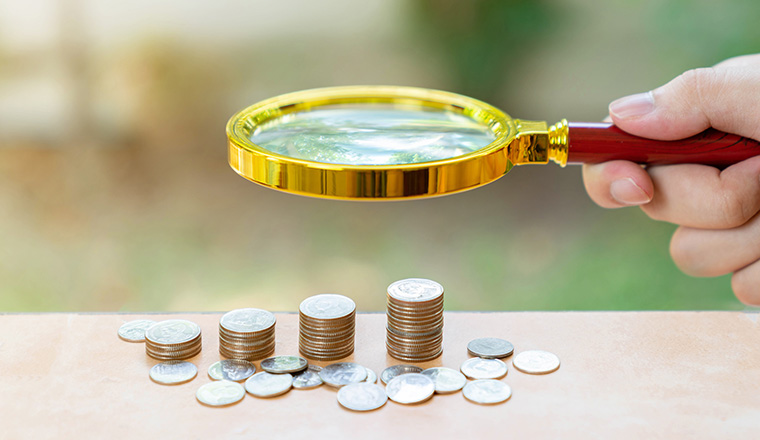 Magnify glass focus money coin stack on out of focus background. Concept of growth up saving and invesment.
