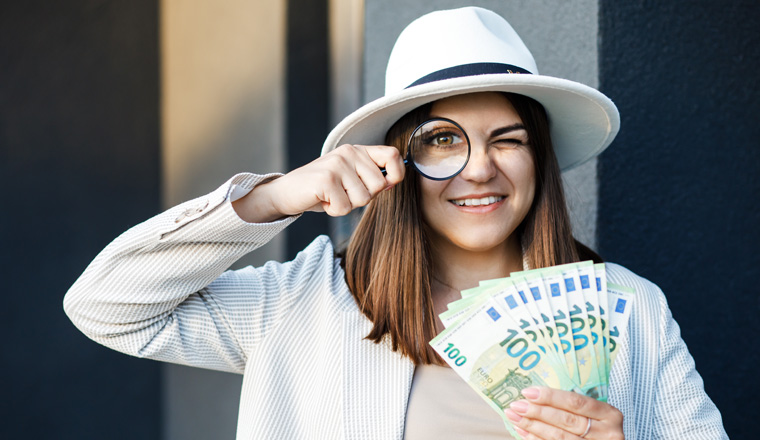 Attractive woman with cash in her hands and magnifying glass.
