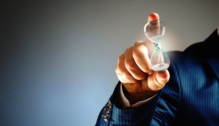 Businessman holding hourglass in hand on grey background