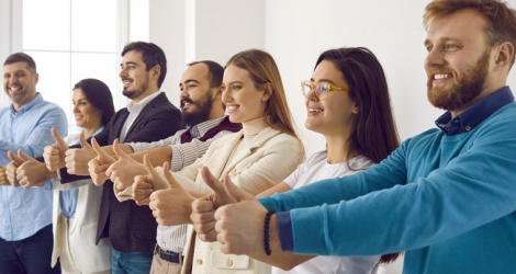 Multiracial group of happy business people showing thumbs up all together. Cheerful male and female employees standing in office, giving thumbs up and smiling. Dream team, teamwork, success concept